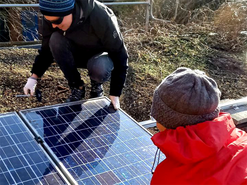 Foto von Bewohnern aus Stedorf, die Solarzellen am Dach anbringen.